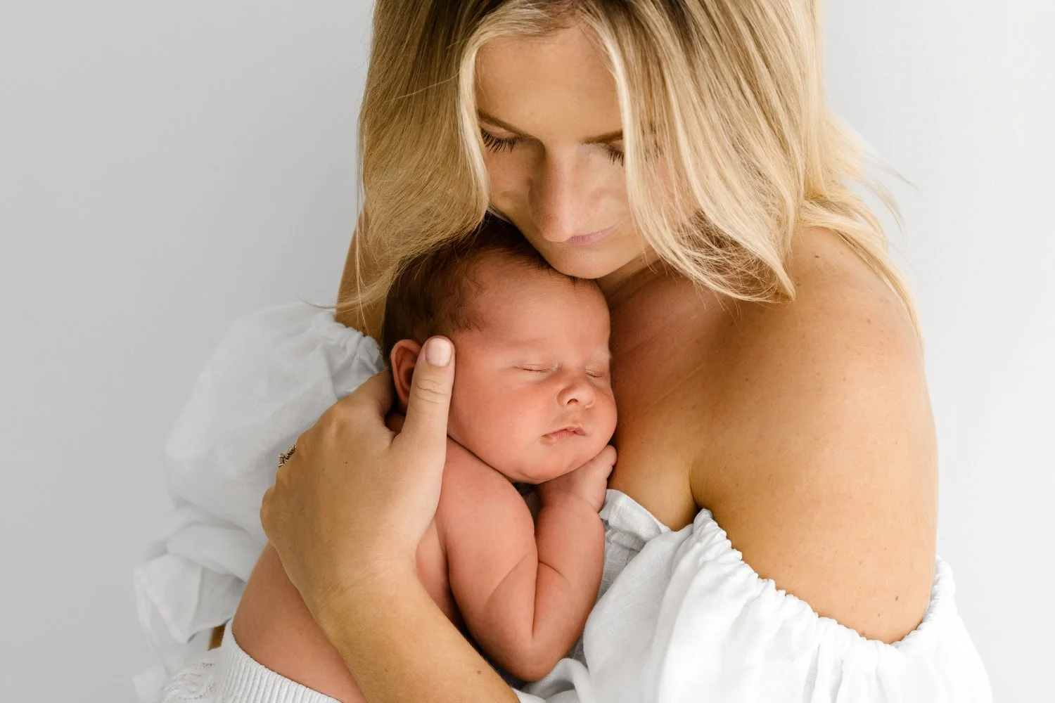 Mum holding newborn baby, soft dreamy background, captured at F6.4