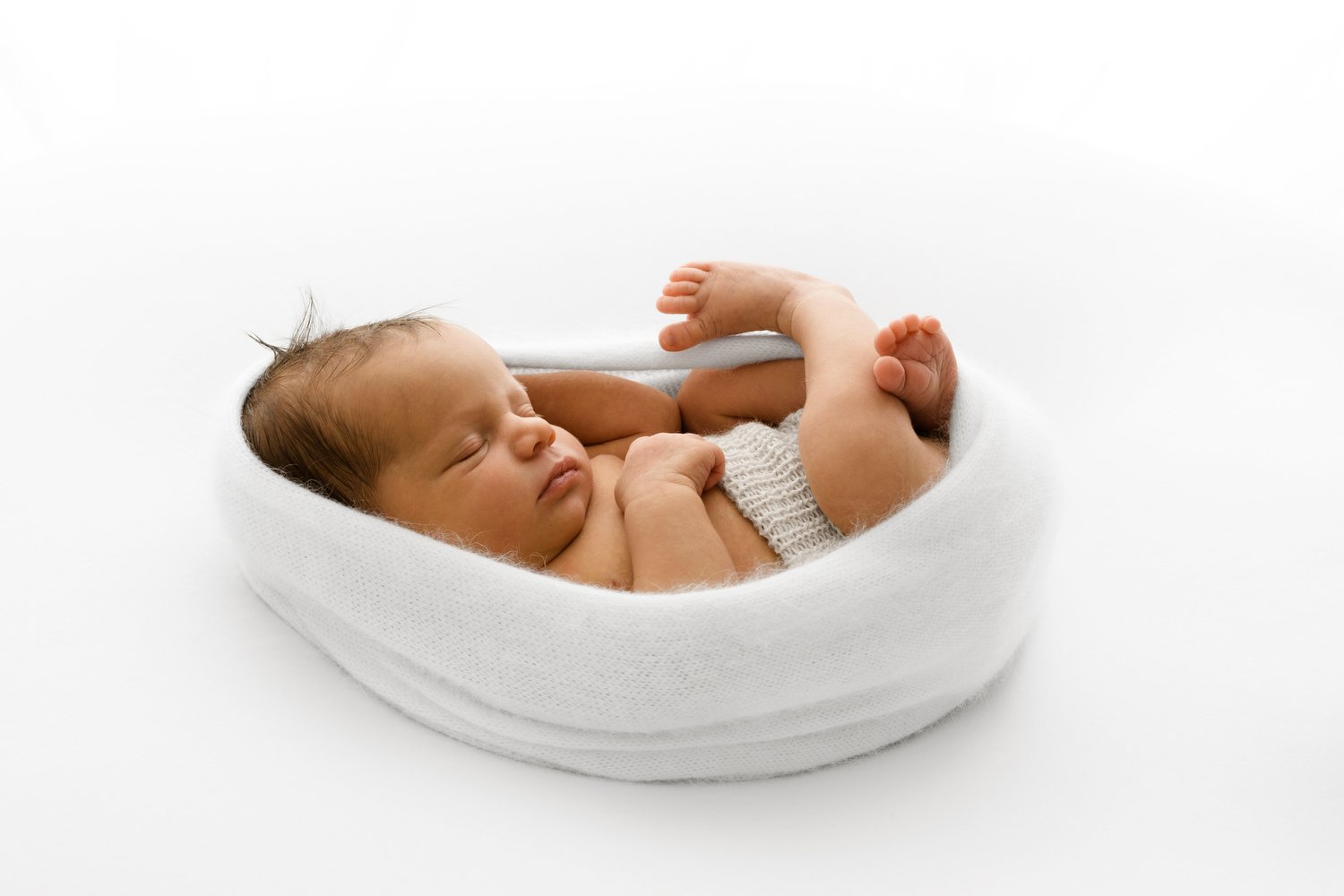 newborn wrapped in simple white style in soft lighting