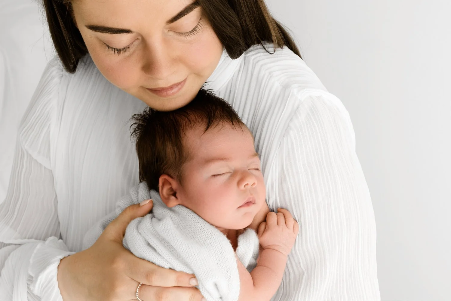 Mum holding settled newborn baby at Mabel and Moose photography studio by Ally Stuart-Ross