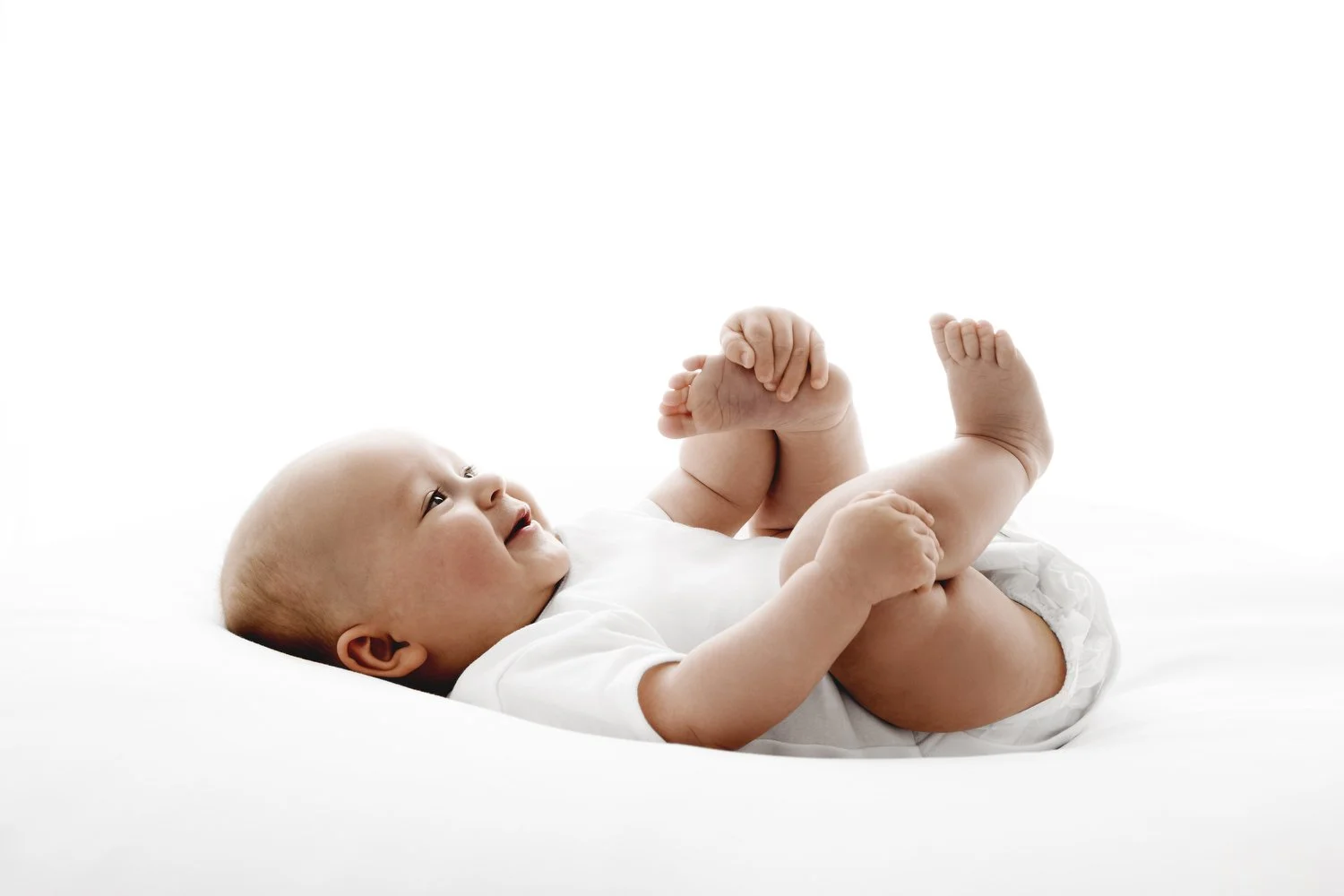 5 month old baby lying on back playing with toes by Ally Stuart-Ross Mabel and Moose Education