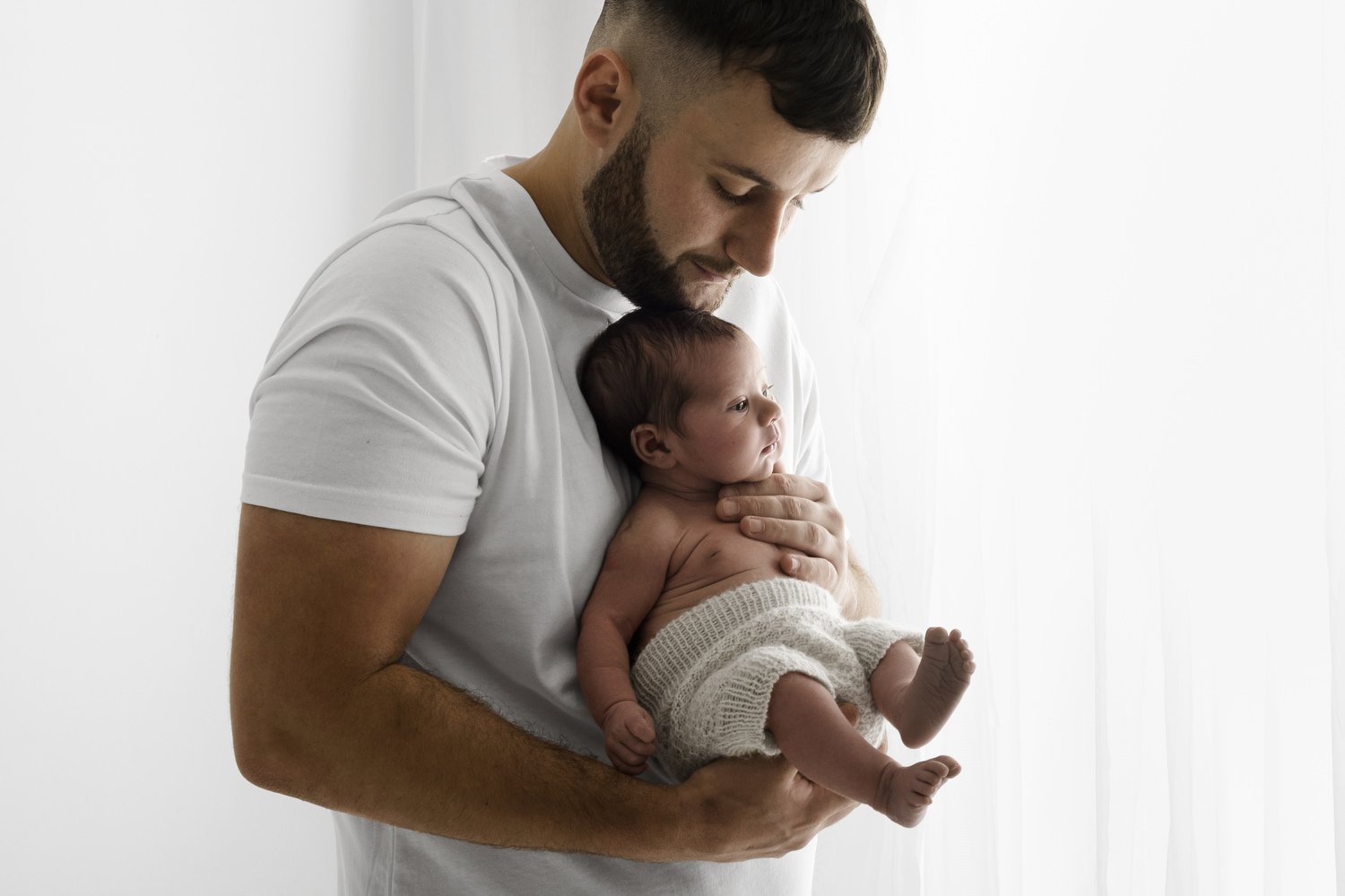 Dad holding newborn baby in beautiful backlit lifestyle newborn photography