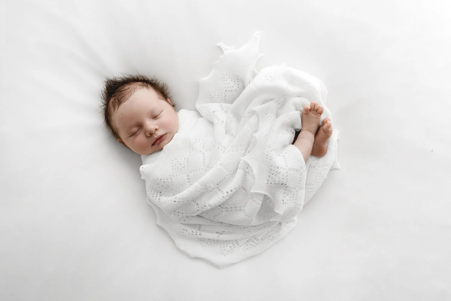 Newborn baby wrapped in white shawl sleeping at Mabel and Moose studio by Ally Stuart-Ross