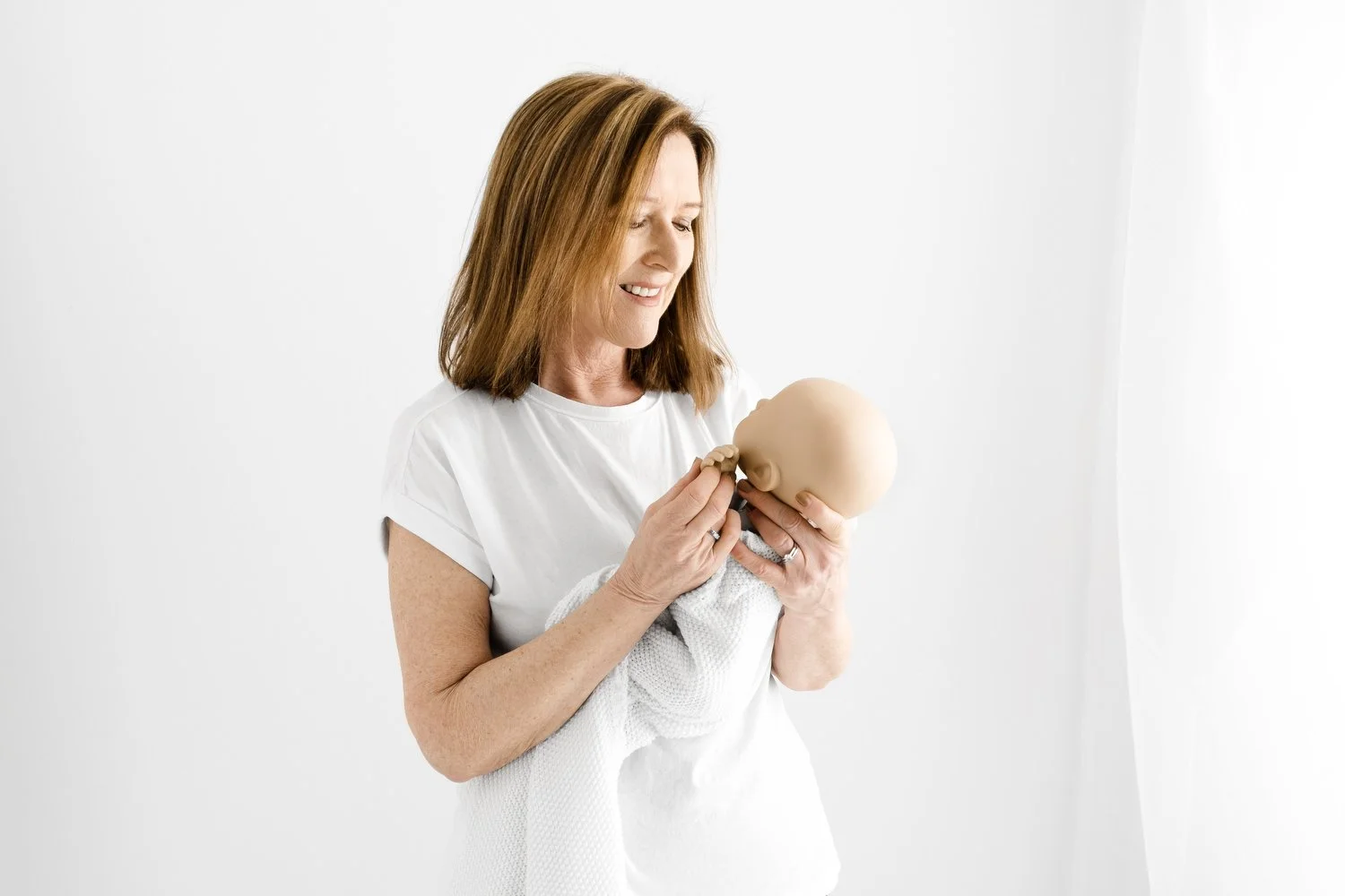 Ally Stuart-Ross demonstrating a minimal style newborn wrap on a StandInBaby realistic training doll during a Fokus online newborn photography mentoring session at Mabel and Moose Education