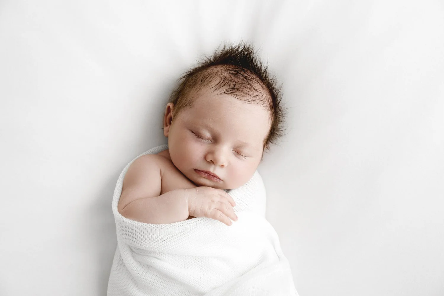 Newborn baby wrapped in white shawl sleeping at Mabel and Moose studio by Ally Stuart-Ross