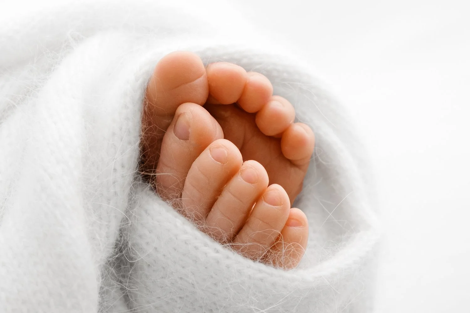 Newborn baby feet tucked in a white knit shawl detail shot by Mabel and Moose newborn photographer