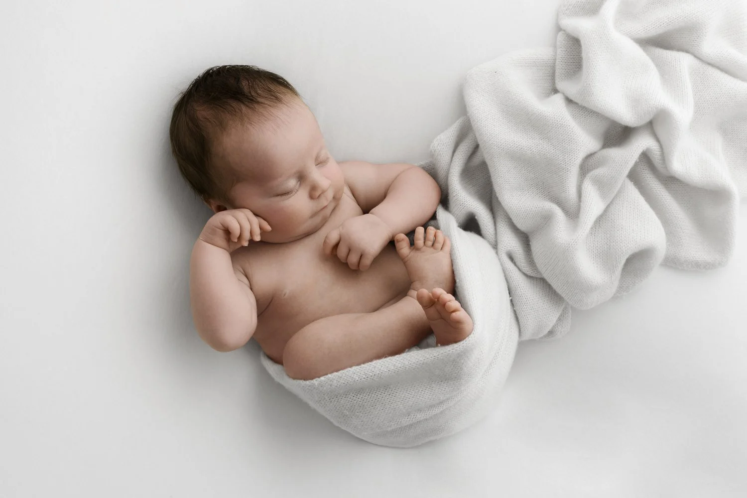 newborn baby sleeping in soft white wrapping material