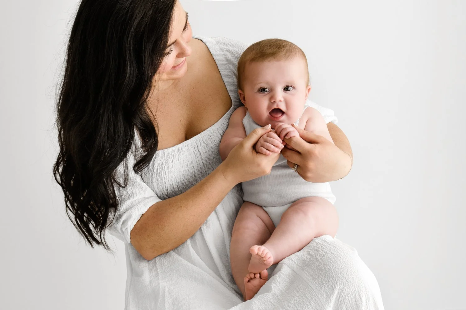 Mum holding older baby, soft dreamy background, captured at F6.4