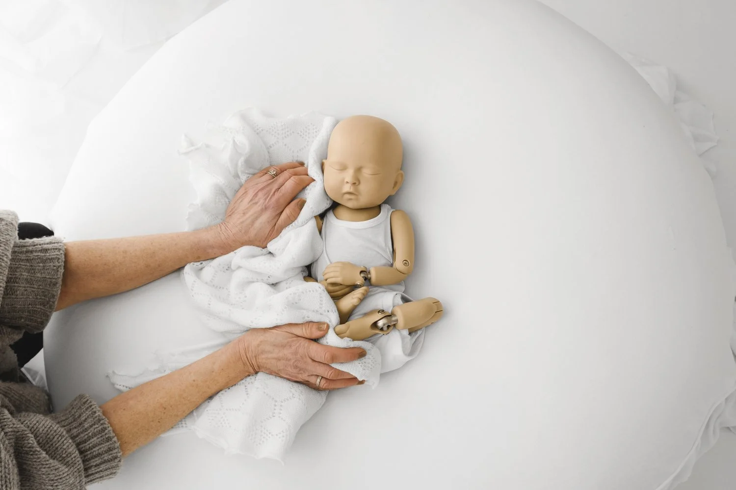 hands on practice at a simple style newborn photography with a stand in baby on a white beanbag