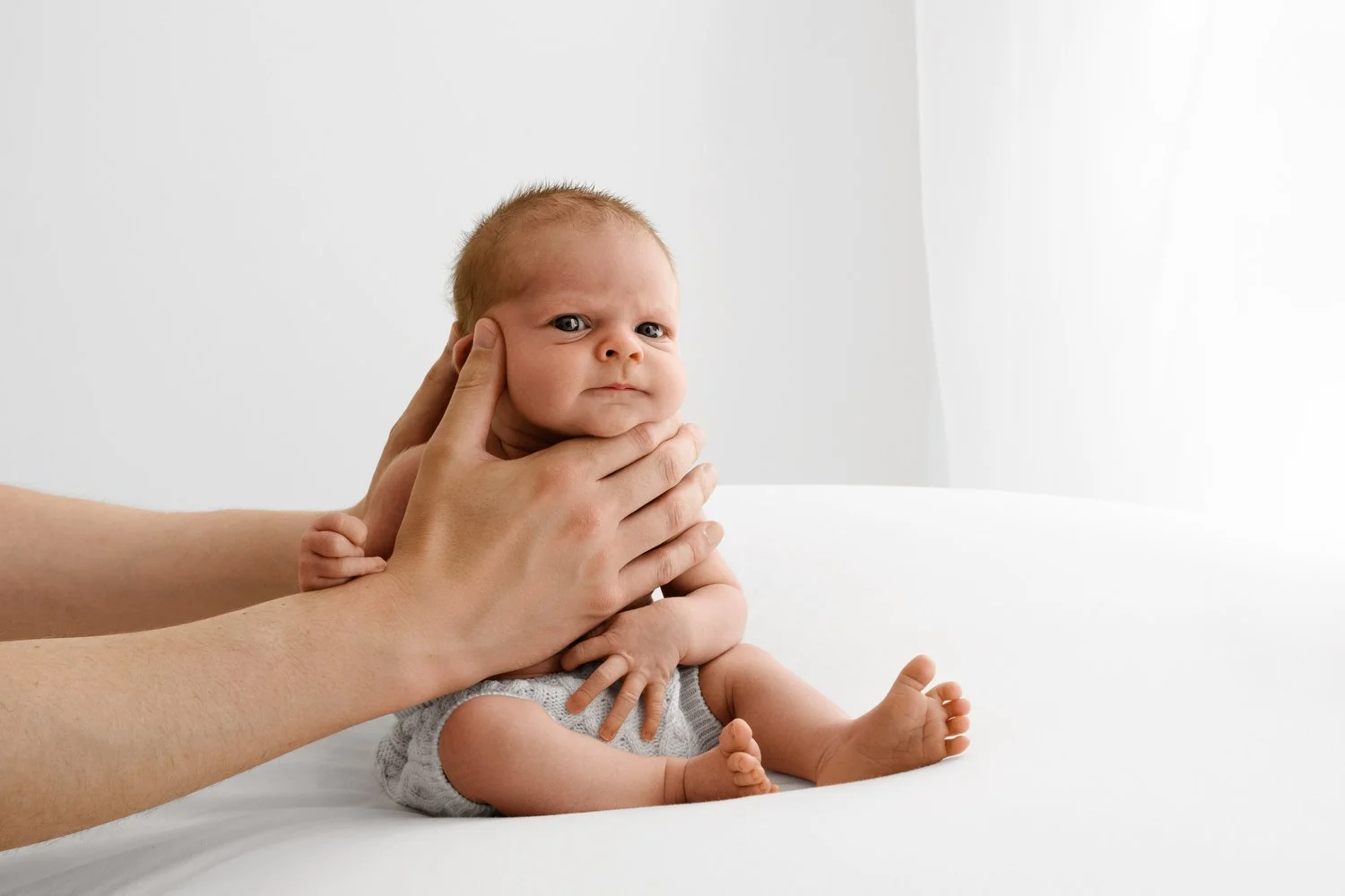 Newborn baby held sitting up awake at Mabel and Moose studio by Ally Stuart-Ross