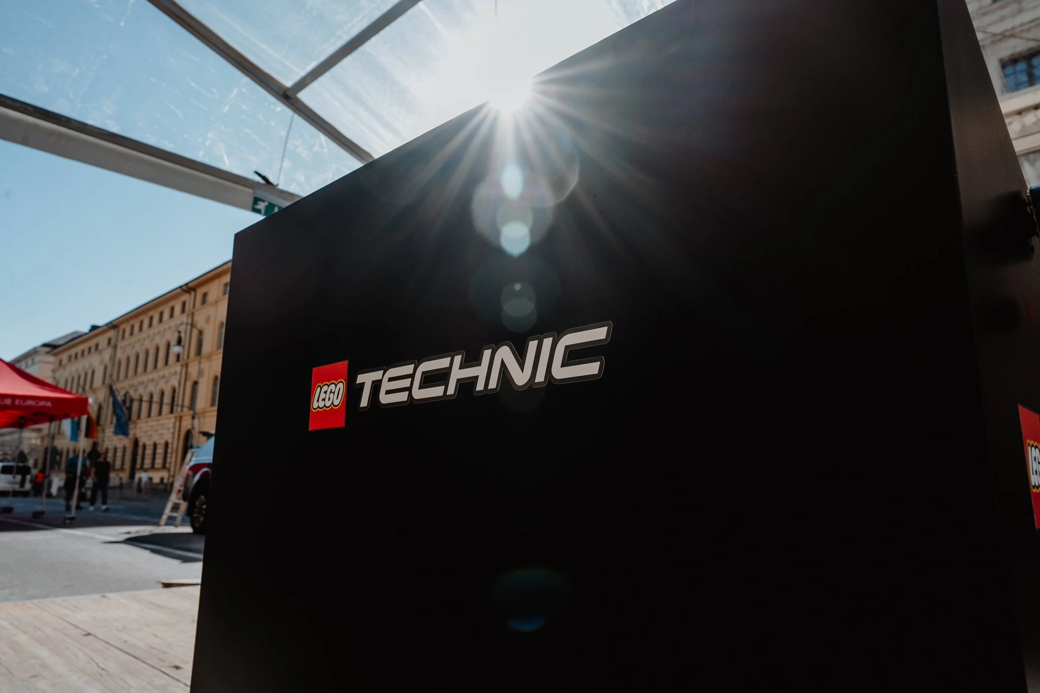 Ein schwarner Kasten mit dem Logo und der Aufschrift LEGO TECHNIC, fotografiert bei sonnigem Wetter, mit Sonnenstrahlen und Lensflare im Hintergrund.