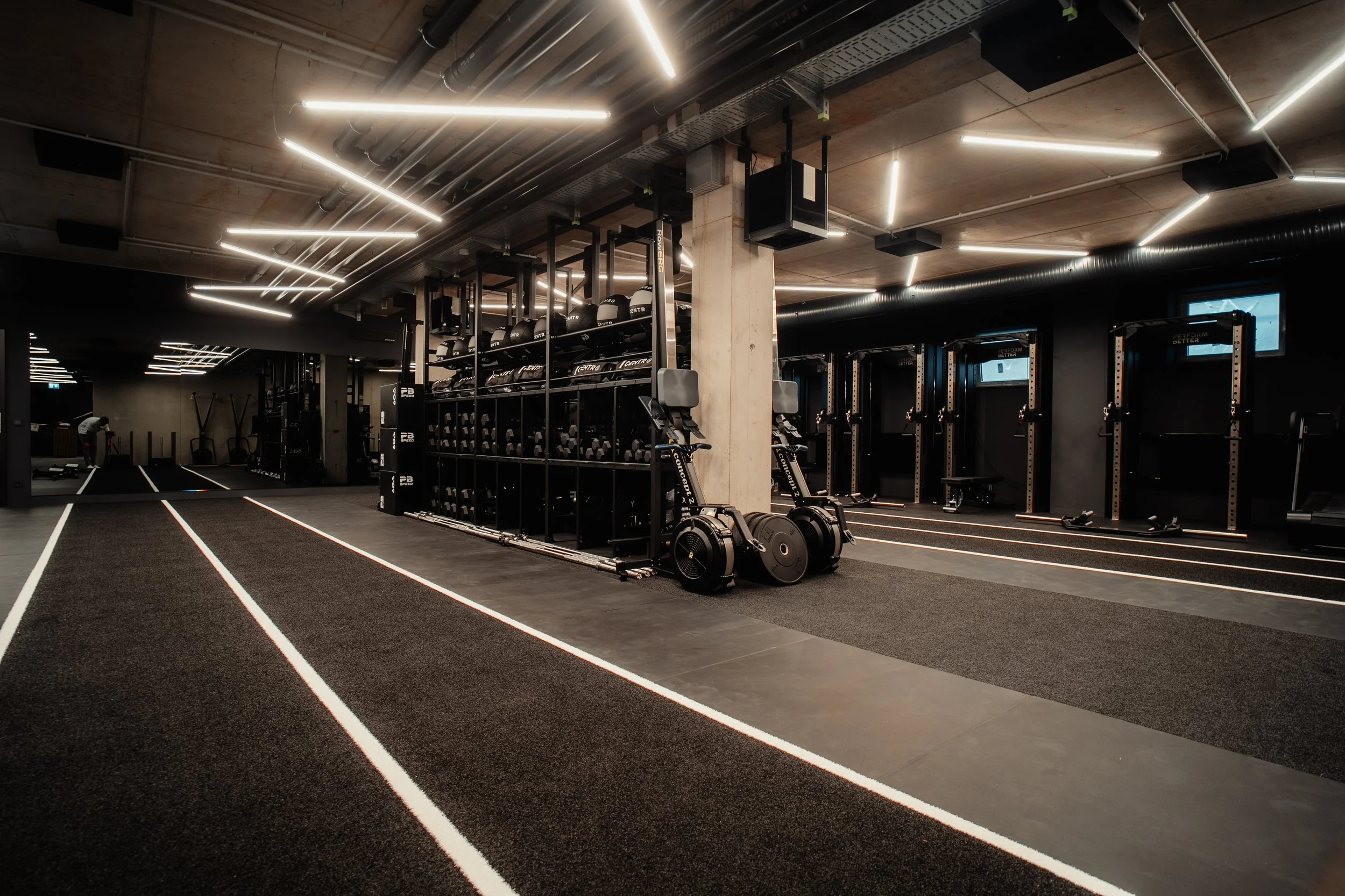 Leerer moderner Fitnessraum mit Laufbahnen, Kraftstationen, Hanteln und medizinischer Ausstattung, gut beleuchtet und modern gestaltet.