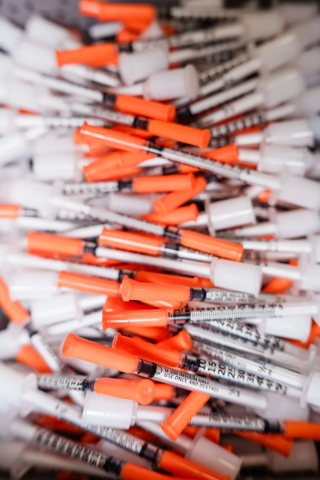Modern house with wooden exterior panels, large front window, and mountain backdrop, situated in a grassy meadow.