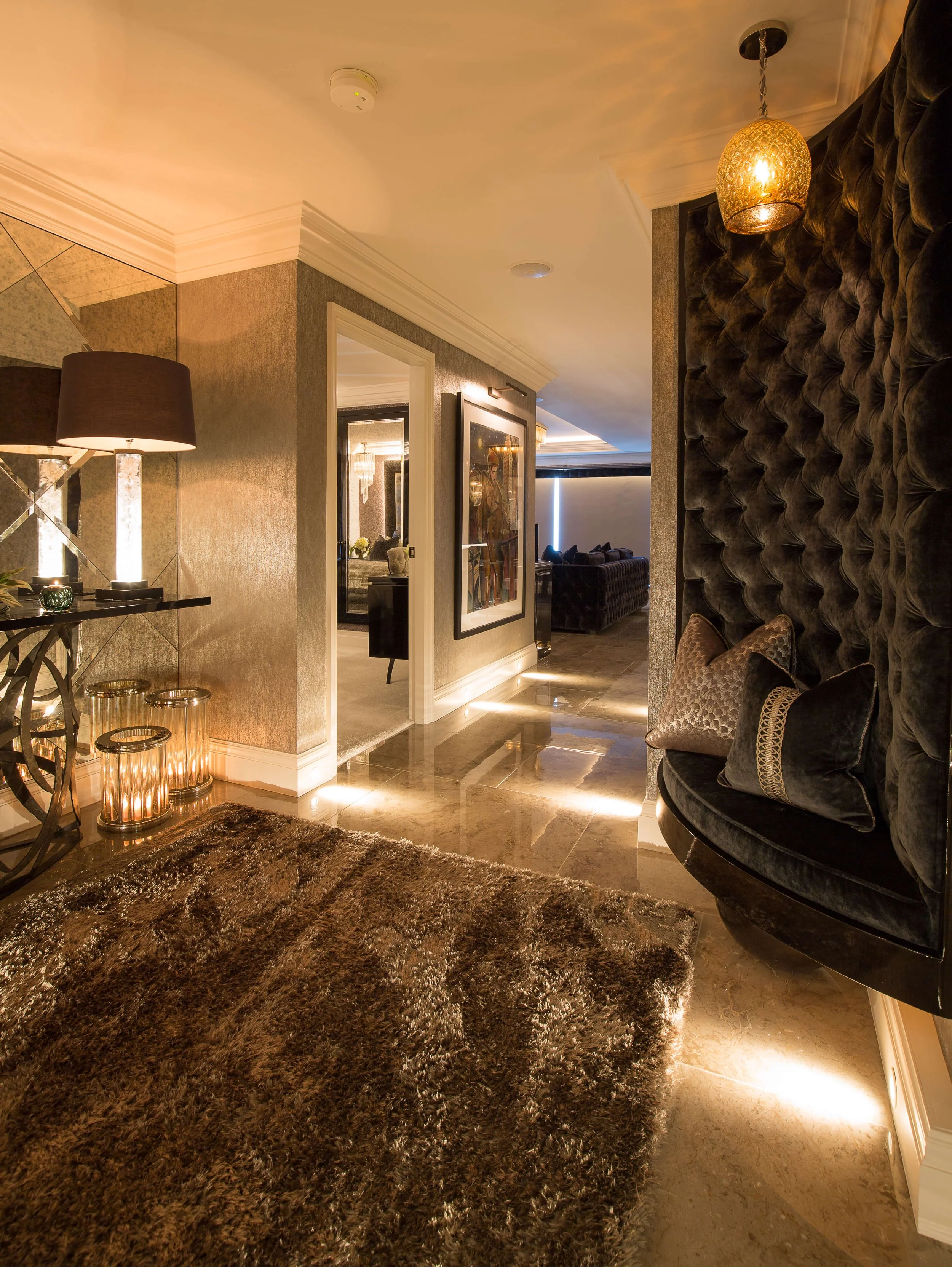 Elegant hotel lobby with plush seating, modern lighting, a shaggy brown rug, and artwork on the wall