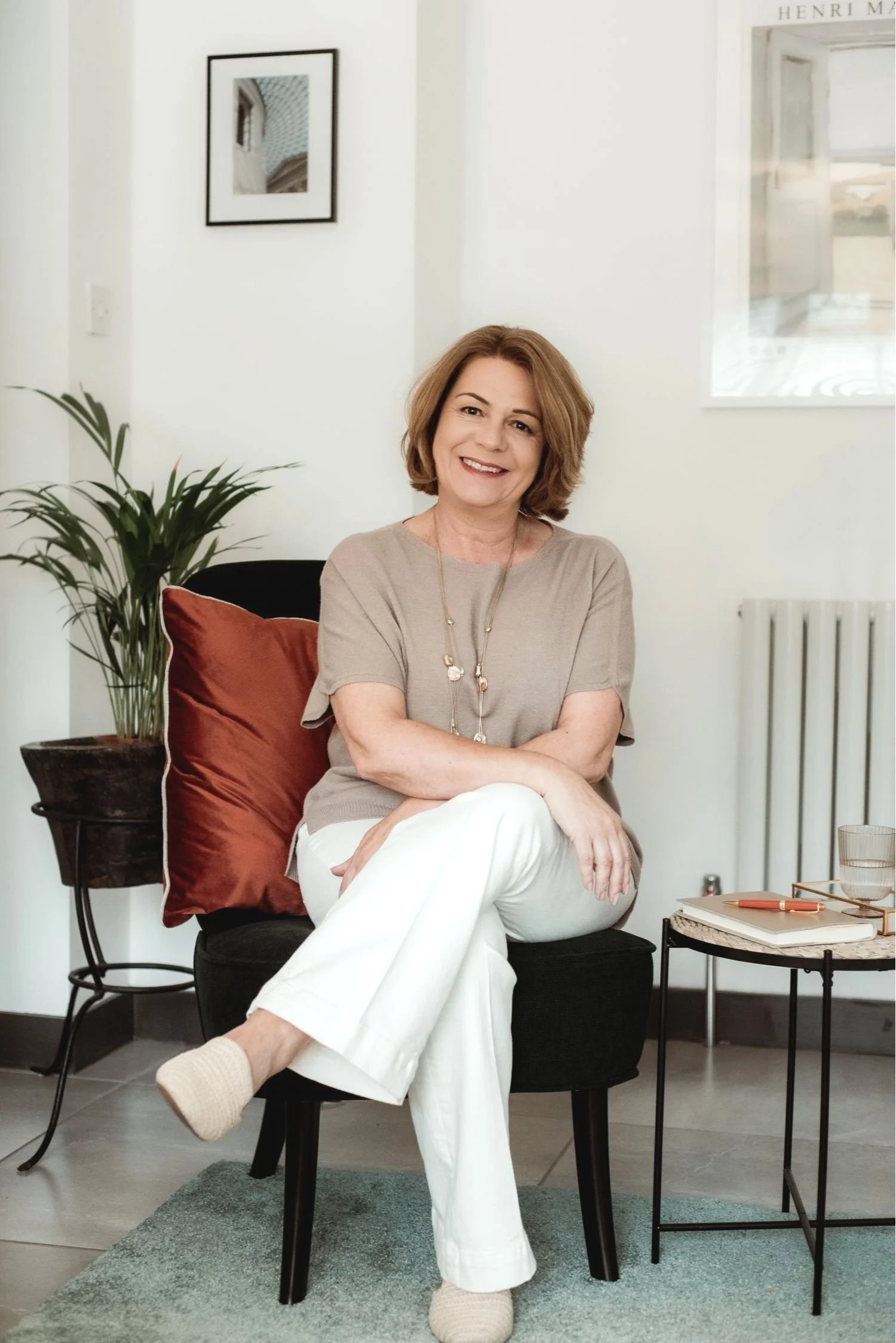 Therapist Lois Dabrowski smiling while sitting on a deep green chair with a rust-coloured cushion