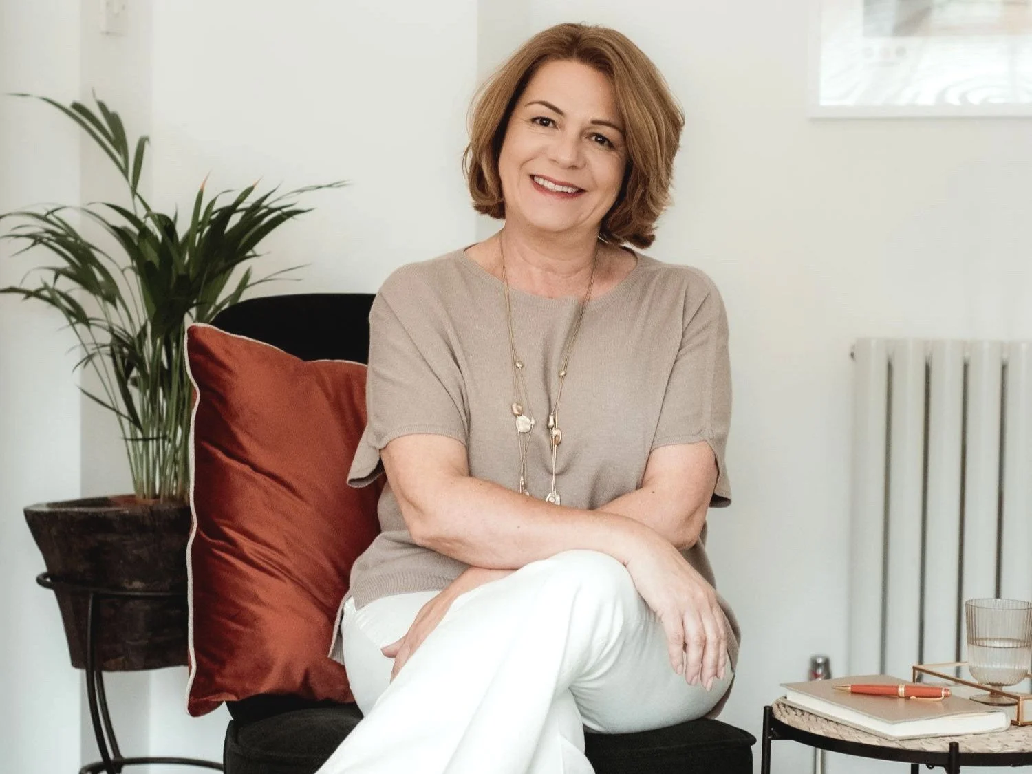 Therapist Lois Dabrowski smiling while sitting on a deep green chair with a rust-coloured cushion
