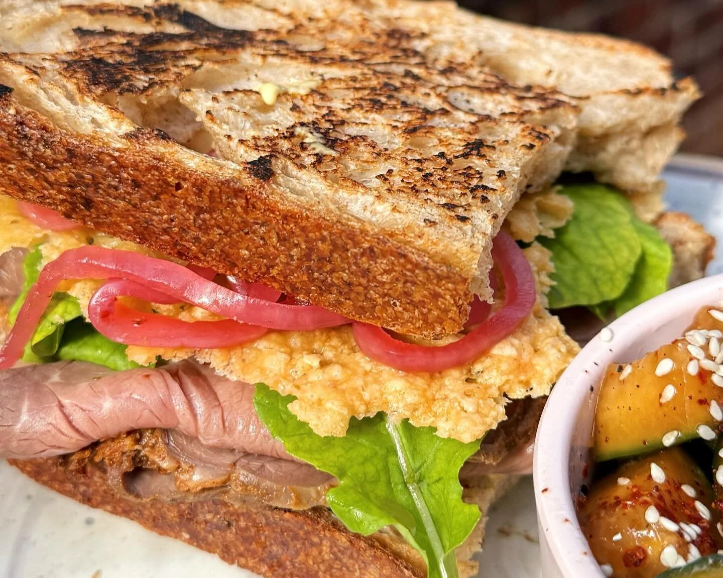 Our Roast Beef Sandwich (w/ a side of marinated cucs, obviously) is a fave amongst our team &amp; arguably one of the most underrated items on our menu 👀

In-house roasted beef, dijon aioli, parmesan crisp, pickled red onion, &amp; arugula on our ho