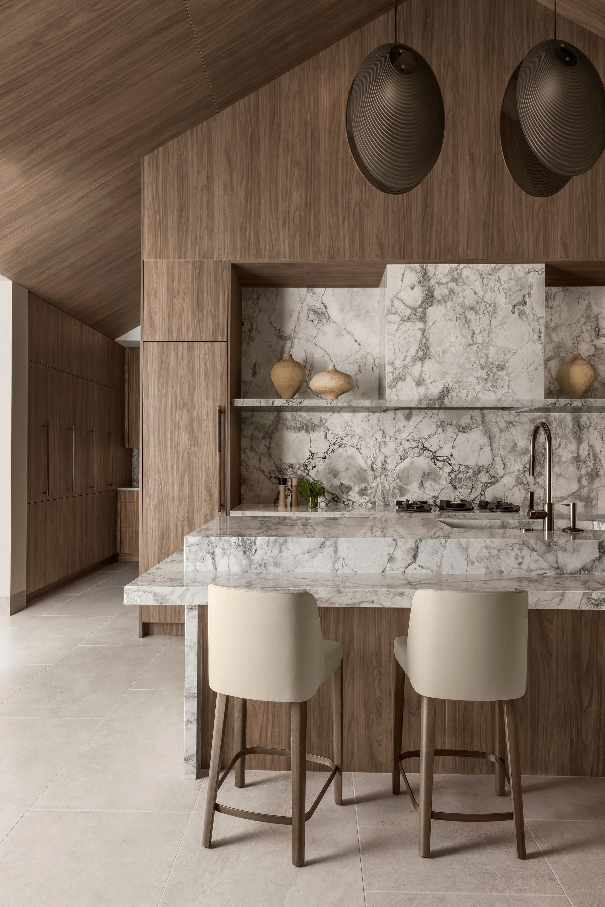 Modern European style kitchen in great room with vaulted, cabinet panel clad ceilings and island surrounded in stone