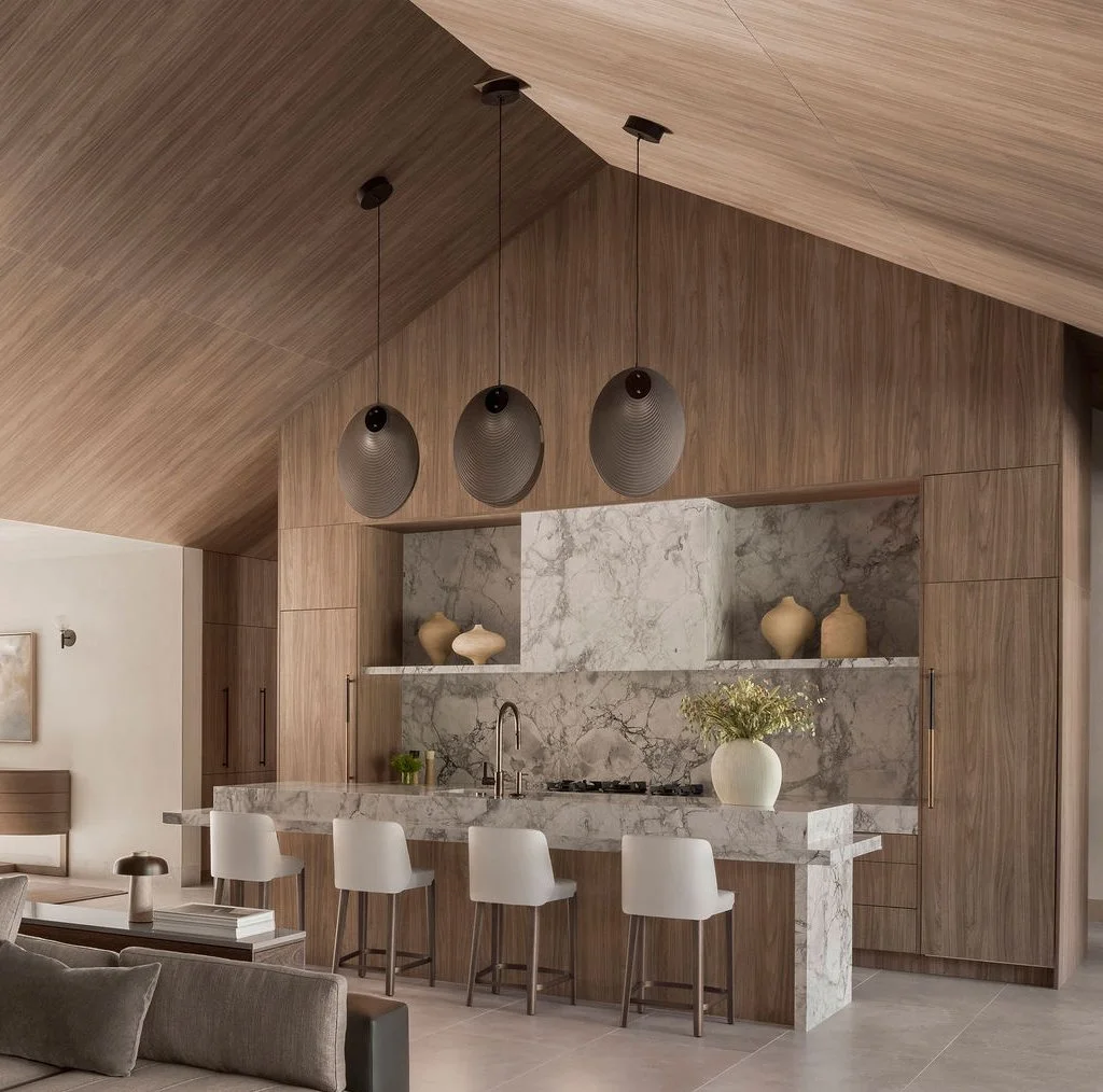 Modern European style kitchen in great room with vaulted, cabinet panel clad ceilings and island surrounded in stone