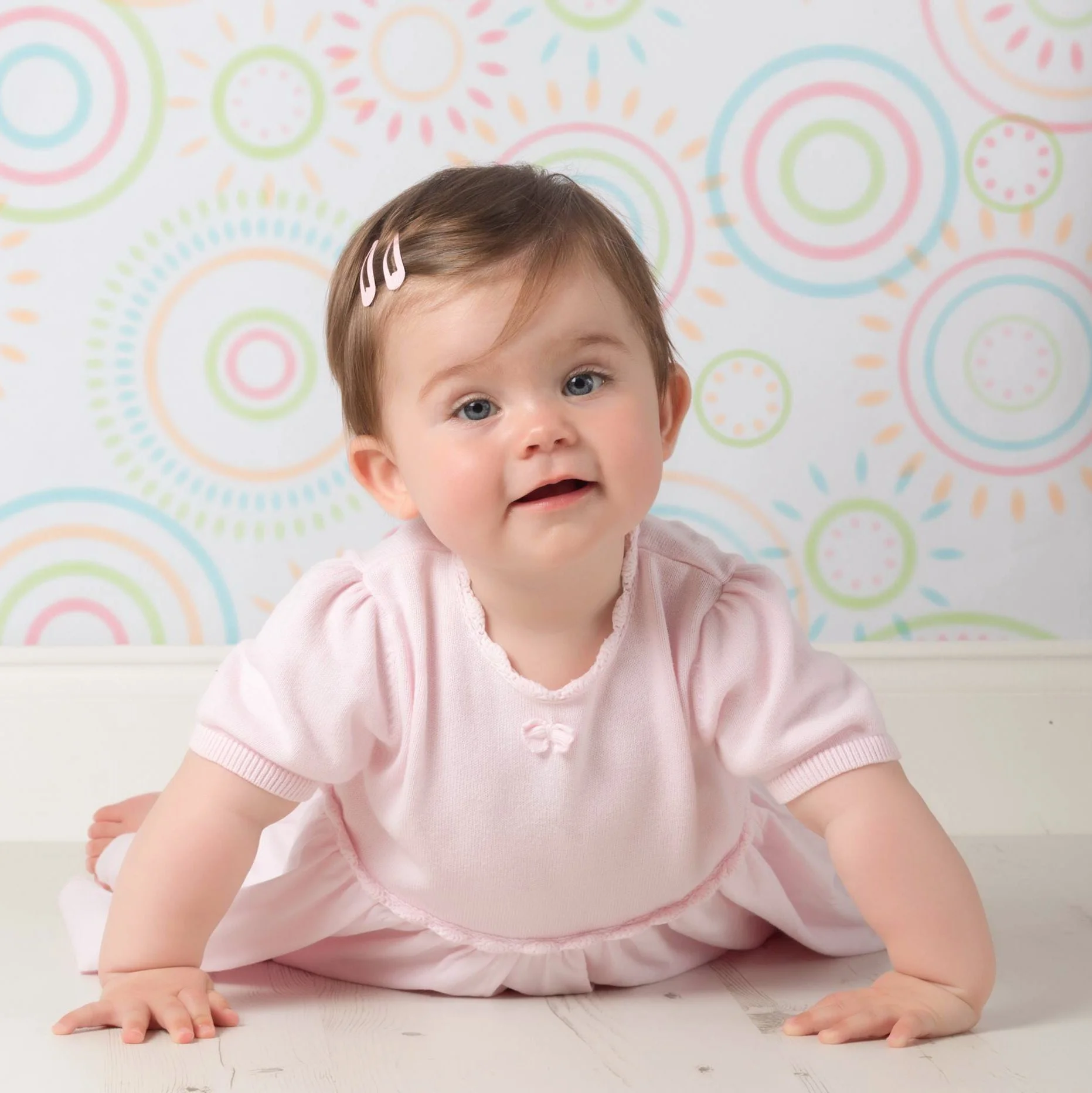 Baby in pink dress against patterned backdrop
