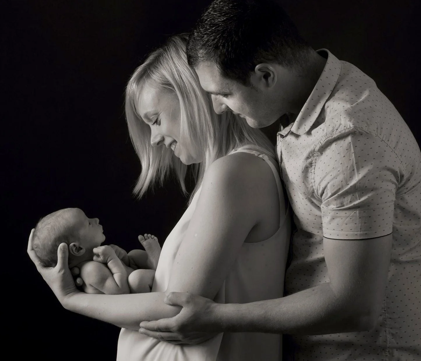 Black and white portrait of mother and father holding their baby