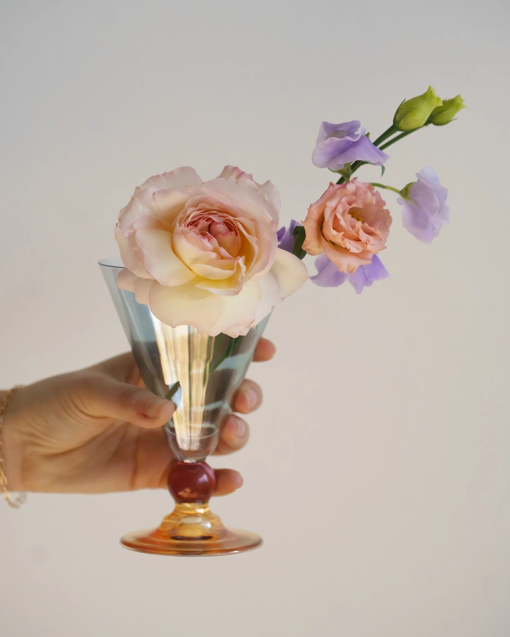Hand holding a decorative glass with pink and peach flowers