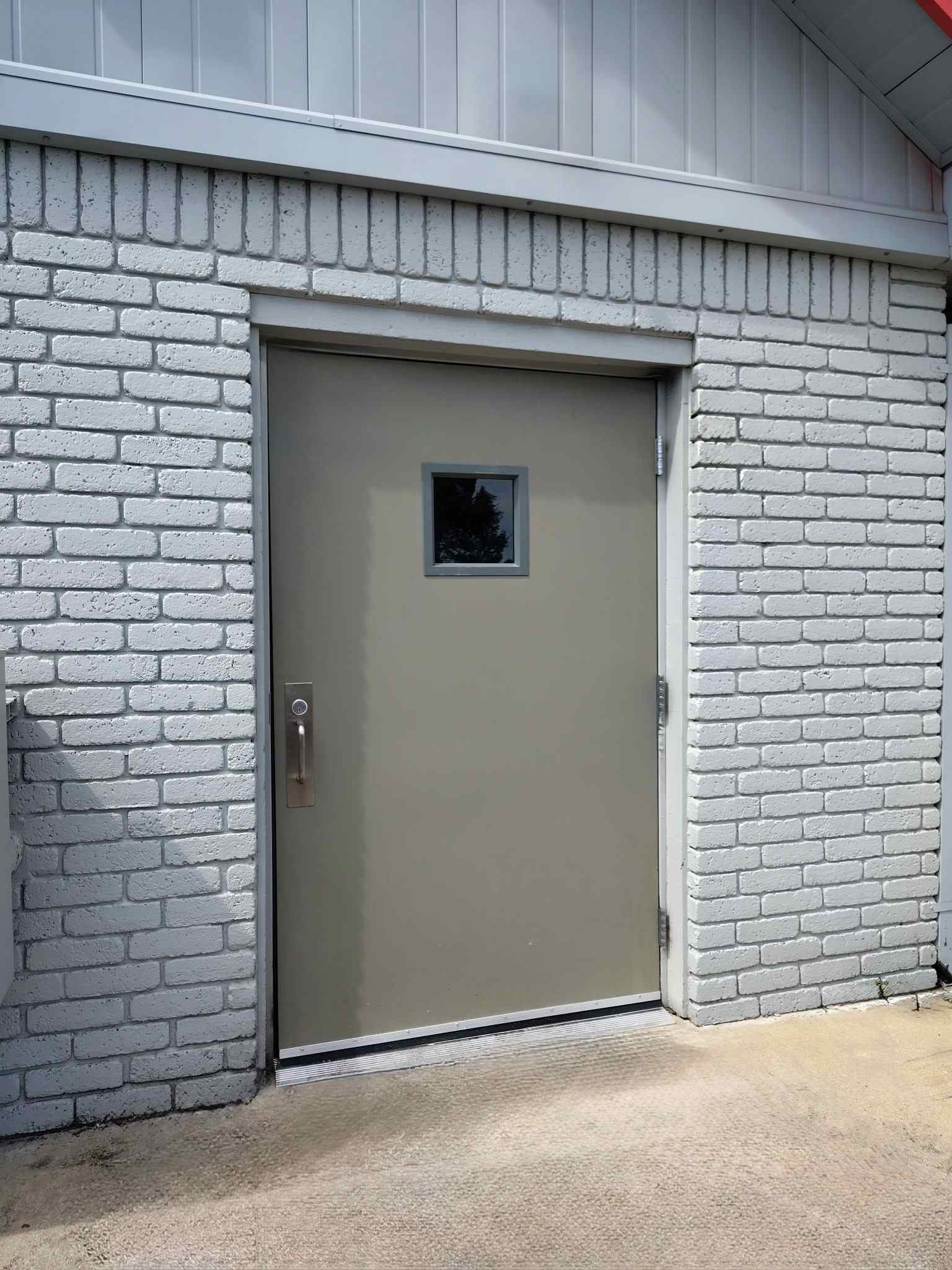 Commercial hollow metal door installation with vision lite in brick building exterior in Muskogee Oklahoma by Apex Doors