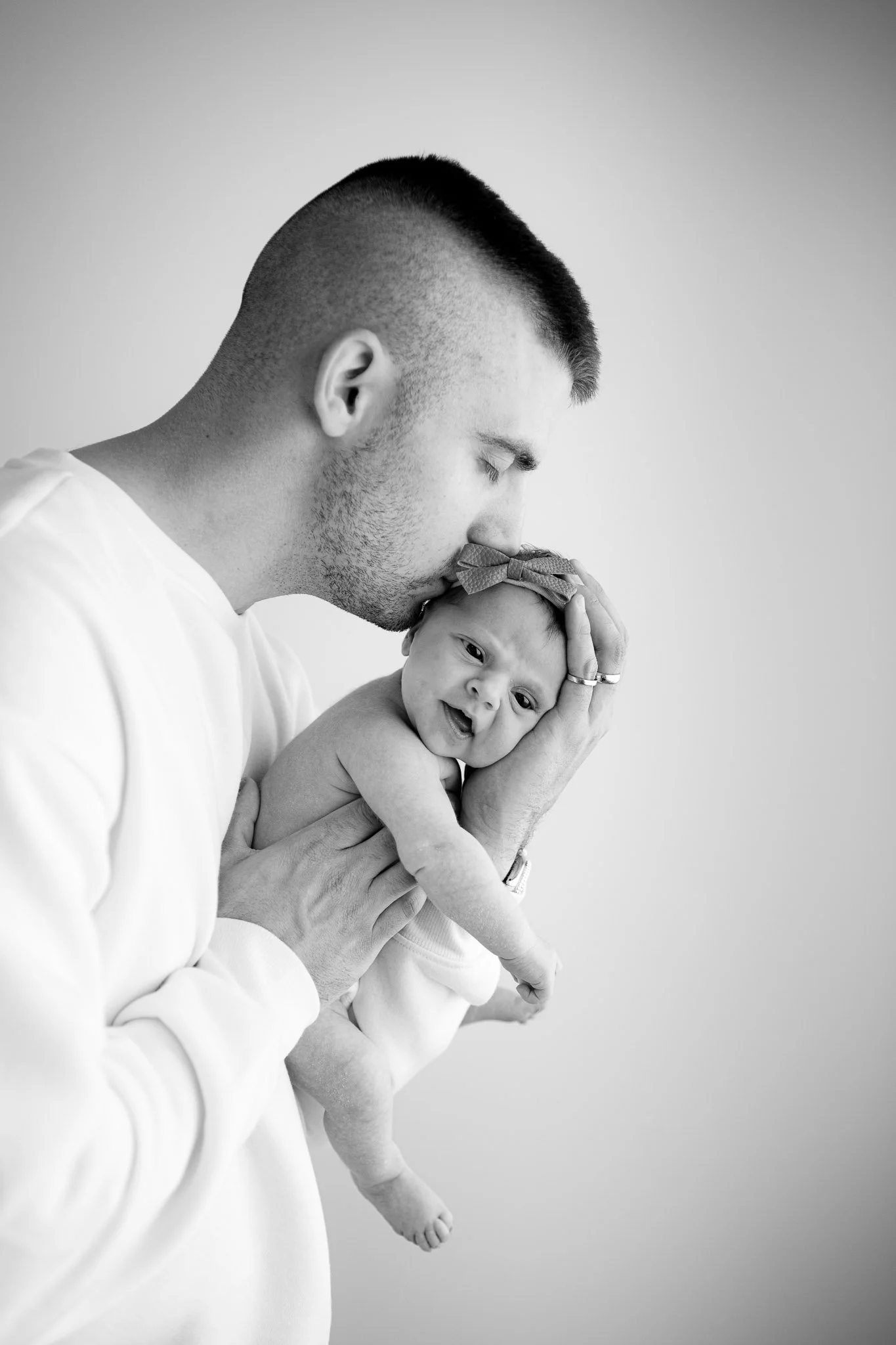 dad kissing newborn daughter on head, studio photography