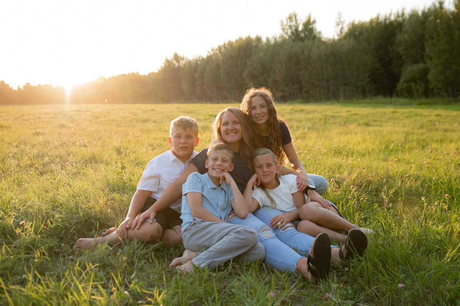 mom surrounded by her children in a field at sunset