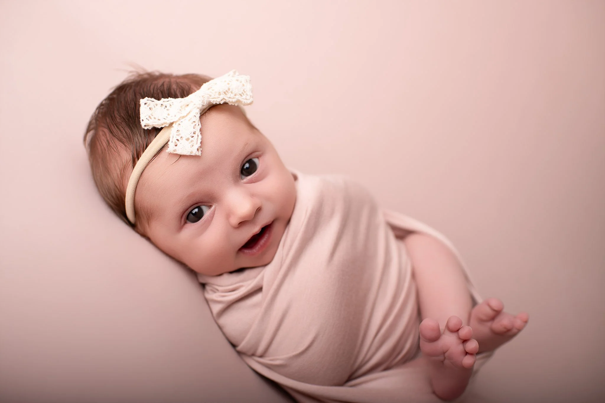 baby girl, smiling, wrapped in pink, studio photoshoot