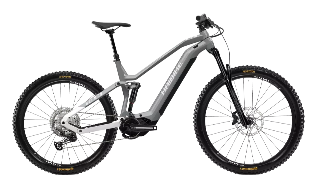 Une bicyclette électrique tout-terrain avec cadre gris, pneus larges, et suspension, vue de profil