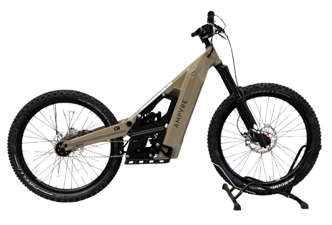 trottinette électrique tout-terrain avec cadre beige, pneus épais, et suspension avant, posé sur un socle.