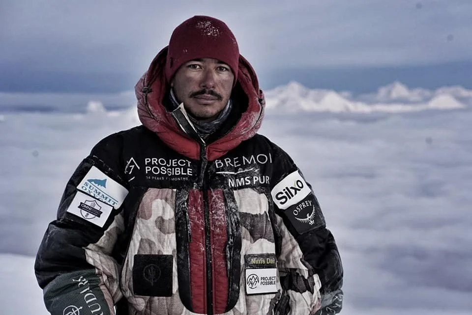 Nimsdai Purja standing above the clouds during Project Possible wearing high-altitude mountaineering gear on an 8,000-meter Himalayan expedition.