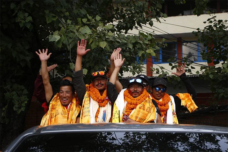 Nirmal "Nimsdai" Purja waving alongside fellow Sherpa climbers during a celebratory homecoming procession in Nepal after a mountaineering expedition