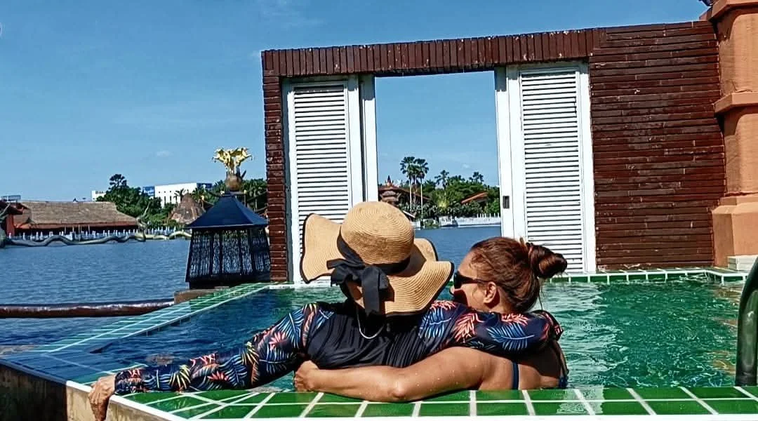 Mother and daughter relaxing in their private villa pool at Ammata Lanta Resort in Bangkok, overlooking the lake on a sunny tropical day