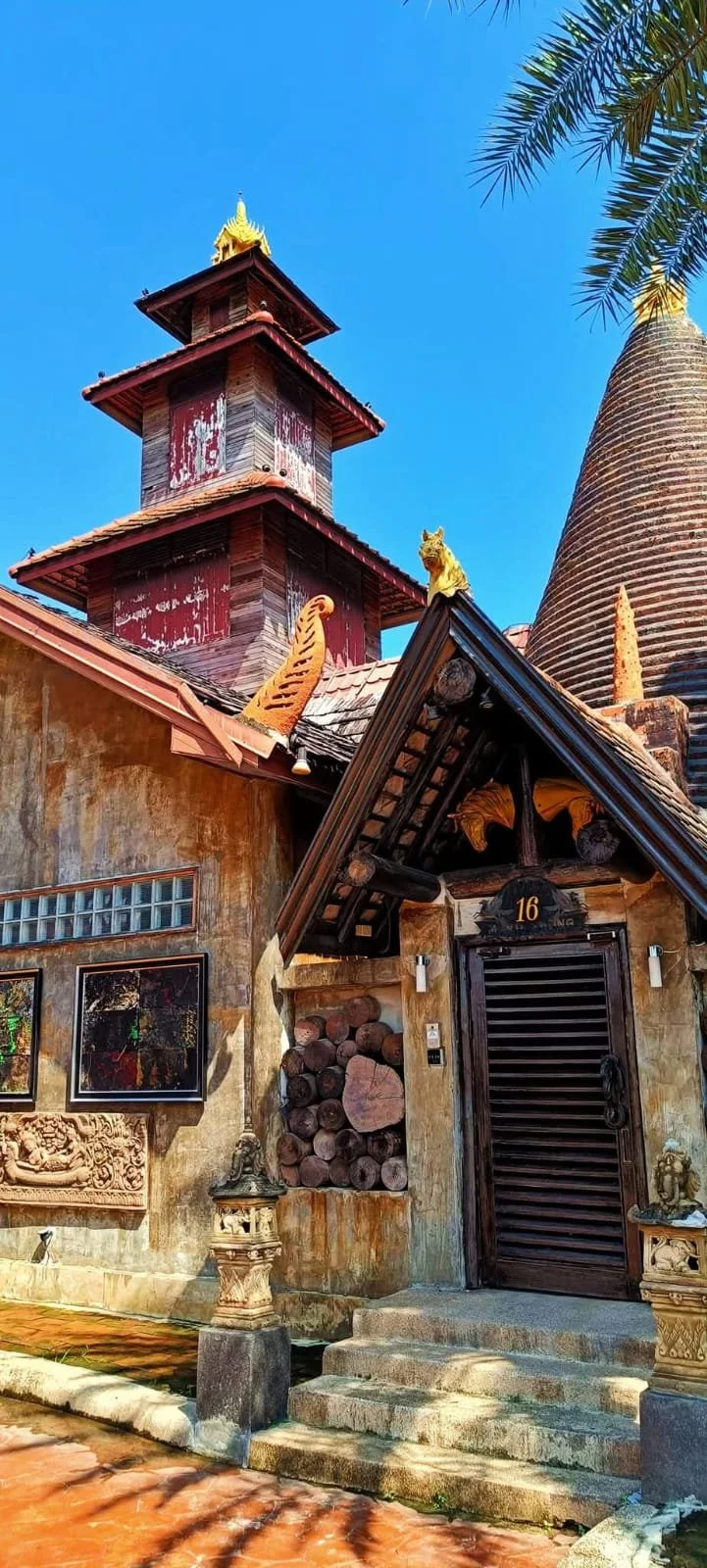 Exterior of Villa 16 at Ammata Lanta Resort in Bangkok, showcasing traditional Thai-inspired architecture, carved details, and rustic wooden elements under a clear blue sky