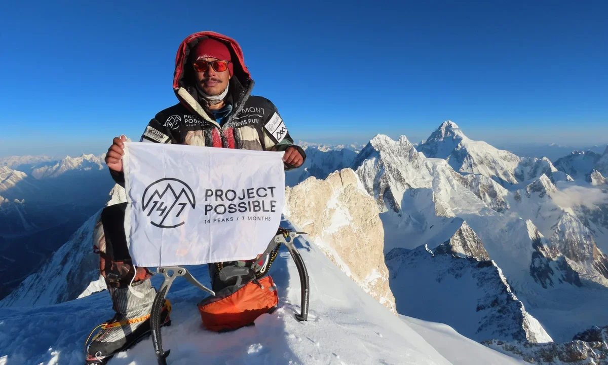 Nimsdai climbing a steep ice wall with two ice axes during a technical mountaineering expedition in the Himalayas.
