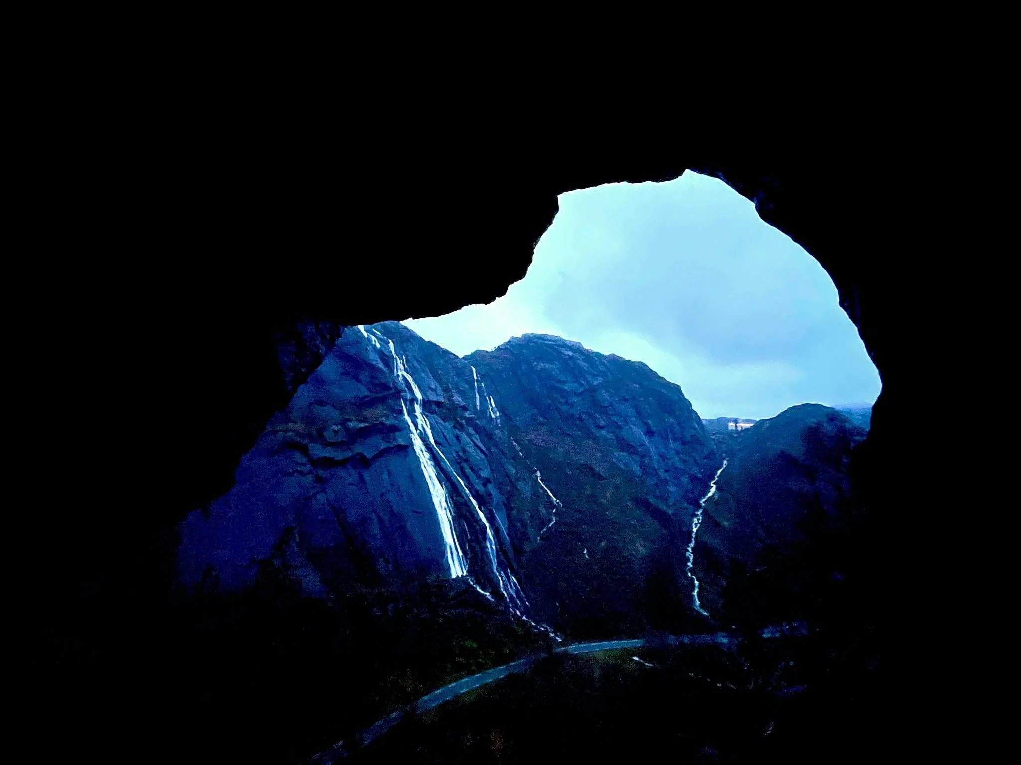 Morning view from inside Tunnelstuo tunnel overlooking dramatic cliffs and cascading waterfalls in Flekkefjord, Norway.