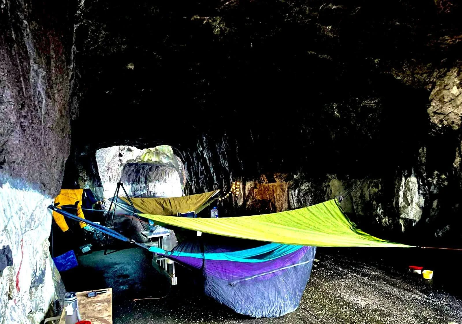 Wild camping hammock and tarp setup inside Tunnelstuo abandoned road tunnel in Flekkefjord, Norway.