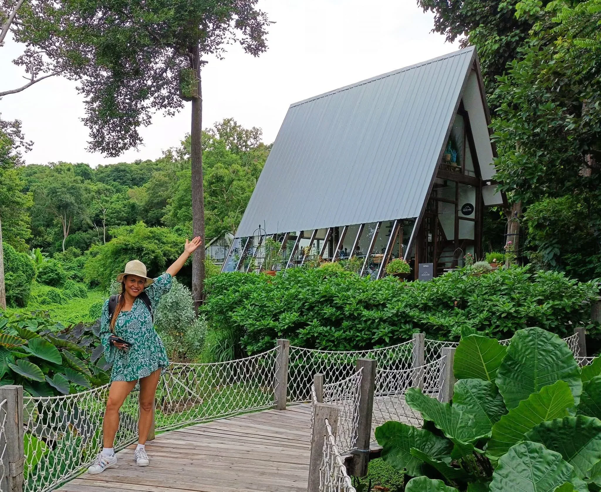 Traveler standing on a wooden bridge leading to Brown Cabin Chocolate Café, a forest-surrounded dessert spot in Koh Samed, Thailand