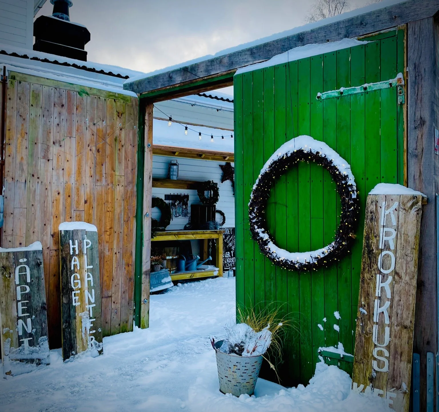 Green wooden entrance of Krokkus Kafé with winter wreath in snow