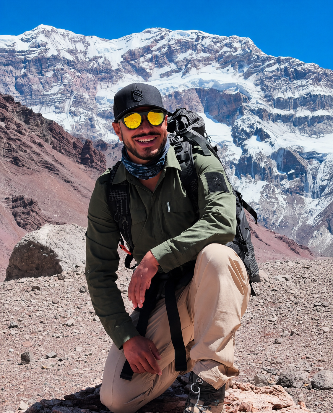 Nimsdai Purja smiling during a mountain expedition with Aconcagua rising behind him in the Andes, showcasing his passion for mountaineering and adventure