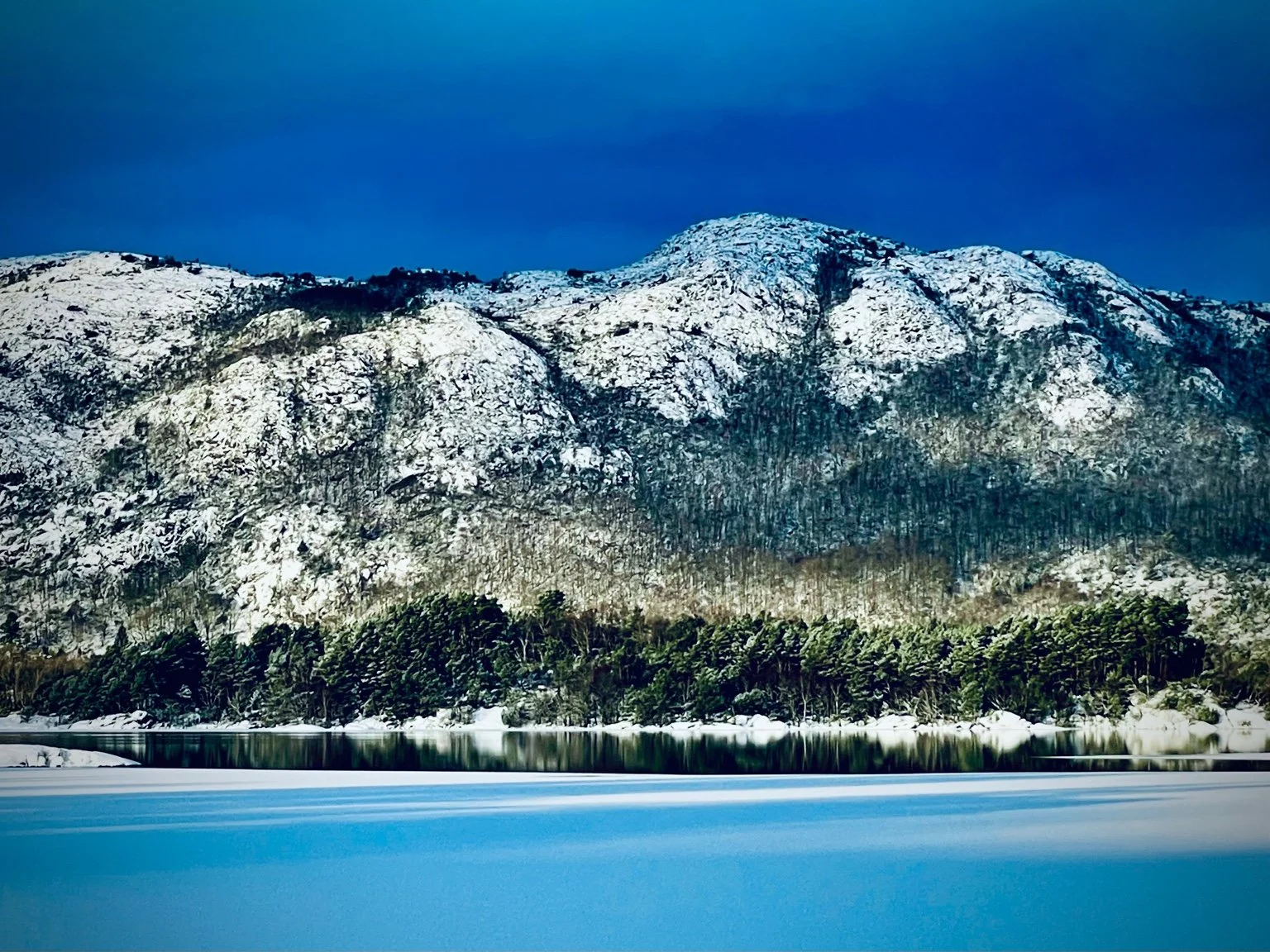 Frozen Lutsi Lake with snow-covered mountains in early winter Norway