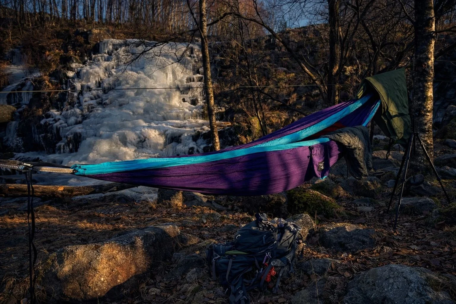Vibrant purple and turquoise hammock set up near frozen waterfall at Sviland Falls, Sandnes