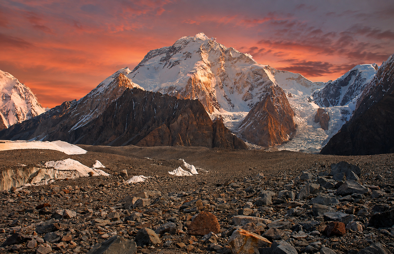 Broad Peak in Pakistan's Karakoram Range illuminated by sunset, showing its snow-covered summit, glaciers, and rugged alpine landscape