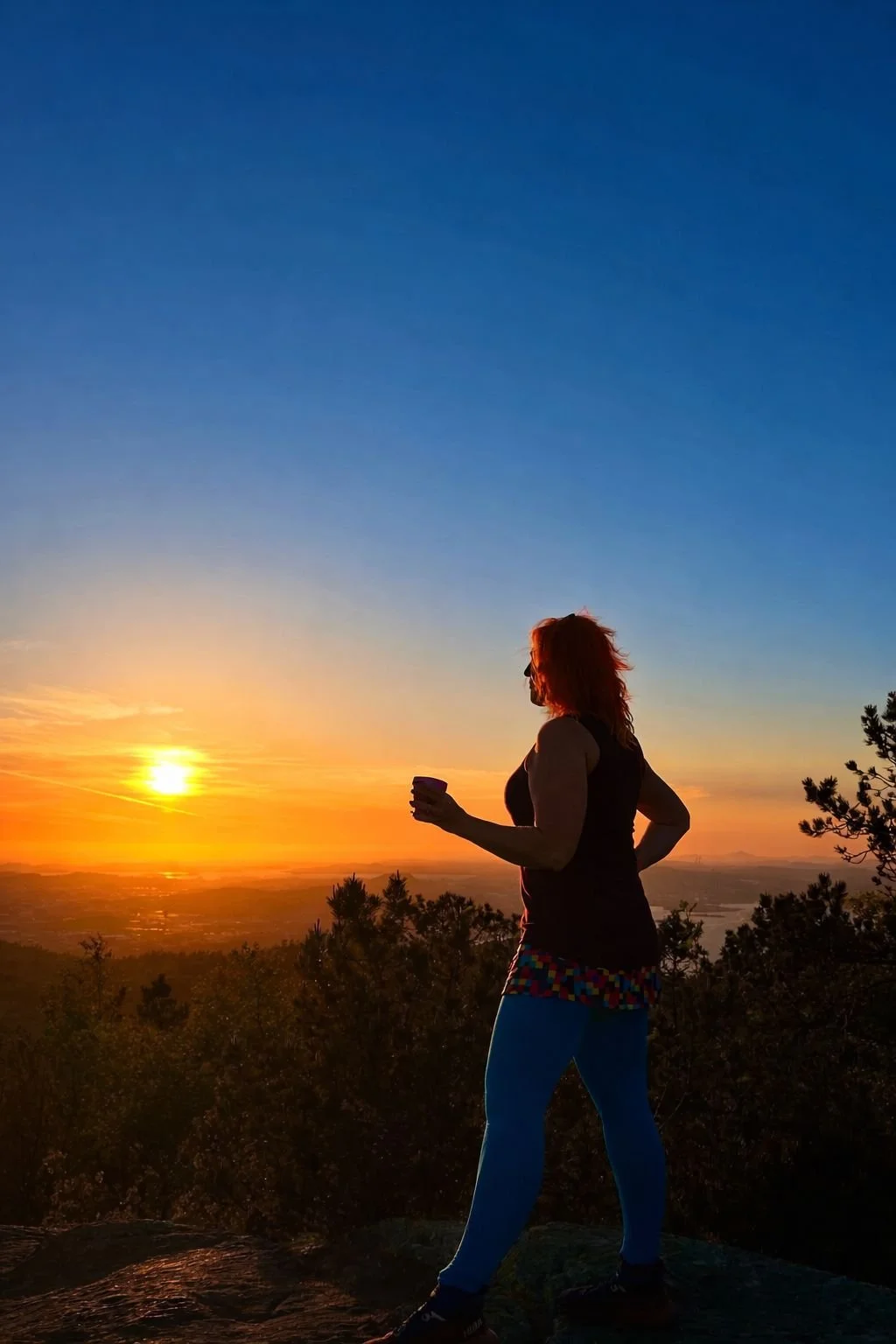 Solveig Fredriksen, Norwegian health coach in Sandnes, Rogaland, overlooking sunset landscape during outdoor wellness moment.