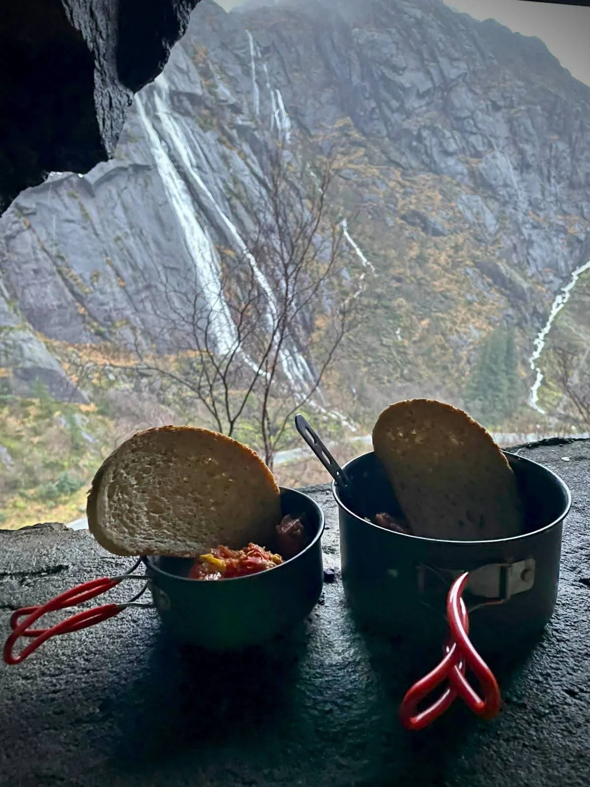 Outdoor camp breakfast inside Tunnelstuo with bread and stew, overlooking a dramatic waterfall in Flekkefjord, Norway
