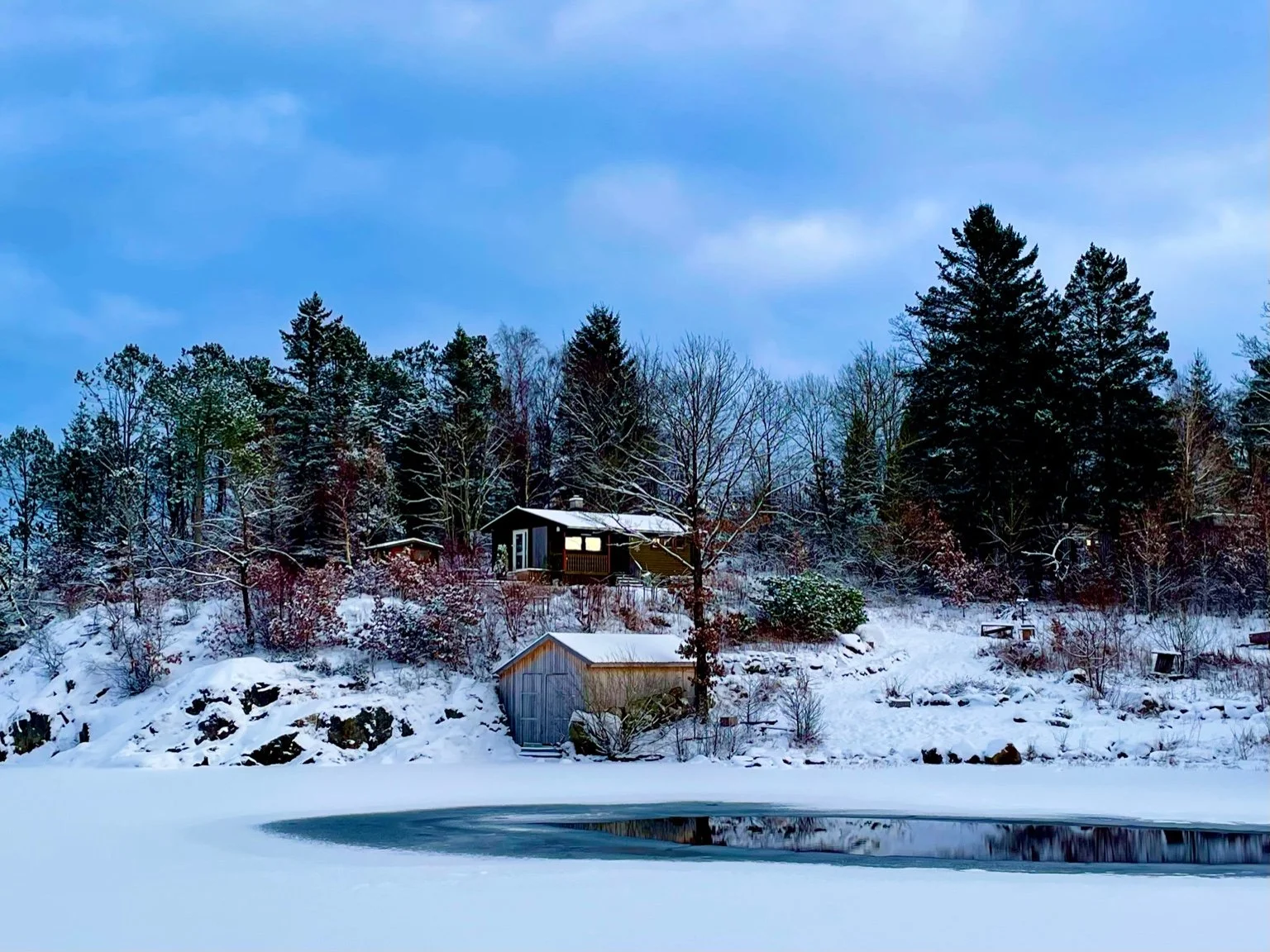 Small winter cabin by frozen Lutsi Lake in Alsvik, Sandnes, Norway, surrounded by snow-covered forest