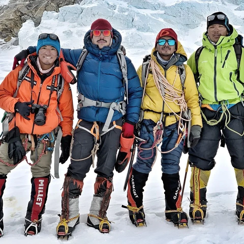 Nirmal "Nimsdai" Purja posing with fellow Sherpa climbers and expedition teammates on a glacier during a Himalayan mountaineering expedition.