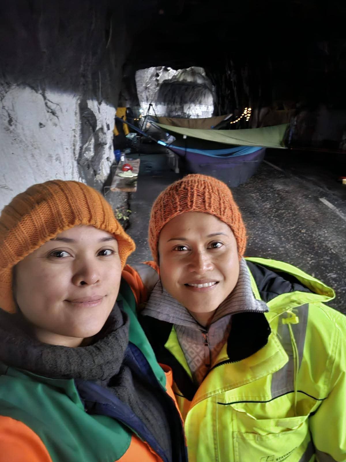 Two campers wearing bright jackets and knitted hats taking a selfie inside Tunnelstuo tunnel in Flekkefjord, Norway