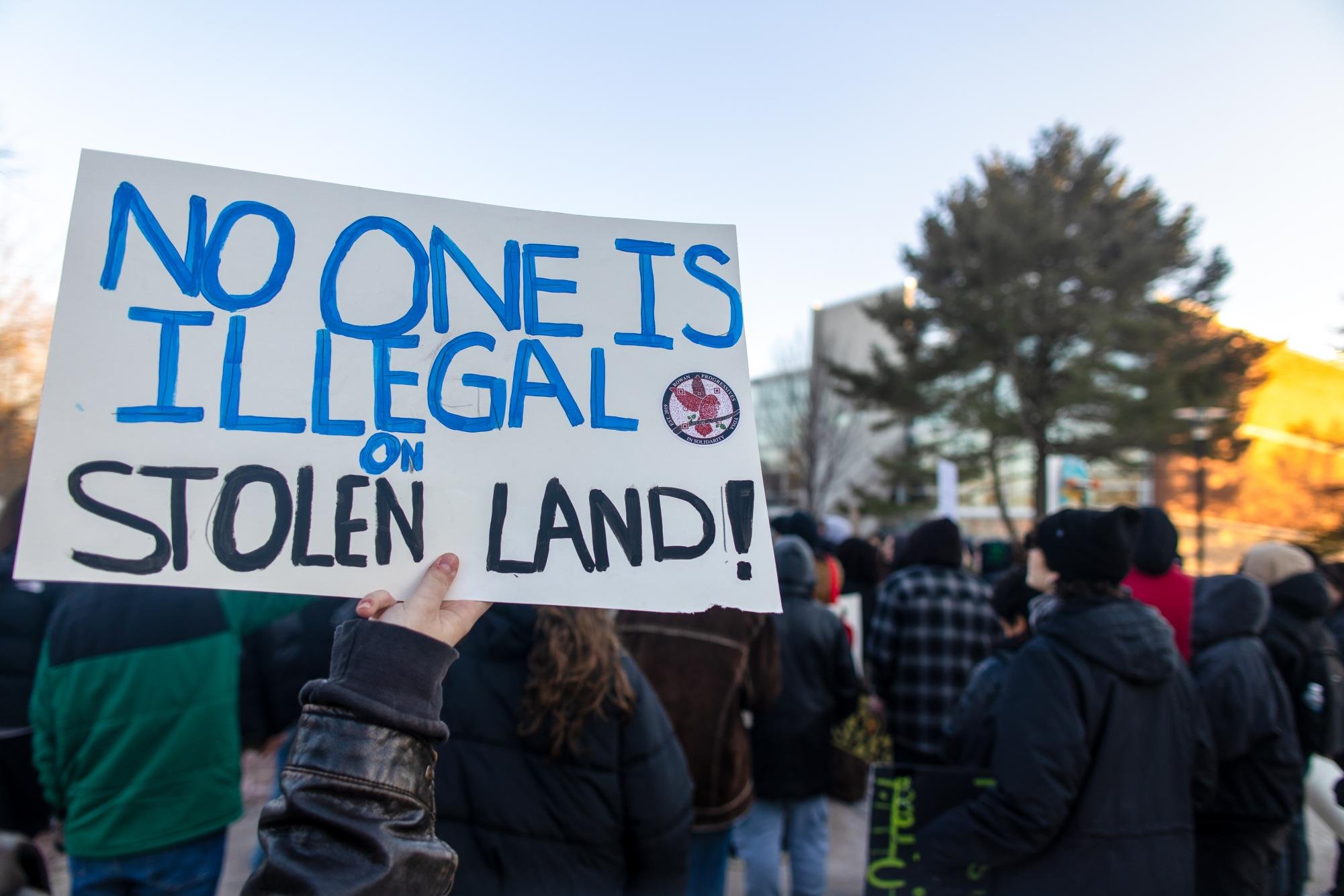  A protestor holds their sign in front of the Owl Statue. Thurs. Feb 5, 2026. Glassboro, N.J. (Photographer: Joe Capuyan) 